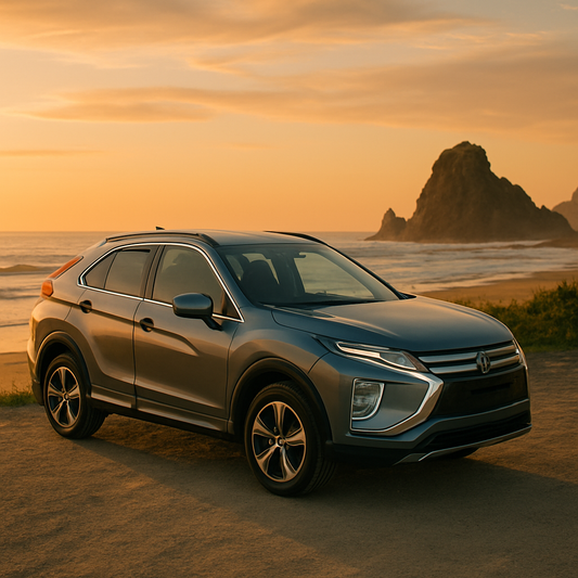 Metallic gray compact SUV parked on a beachside road at sunset, with ocean waves and rock formations in the background — ideal lifestyle scene for roof rack compatibility in New Zealand.