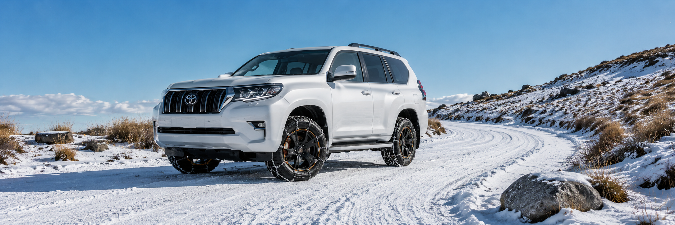 toyota prado on snowy alpine road with tussocks and rocks and konig snow chains on tyres