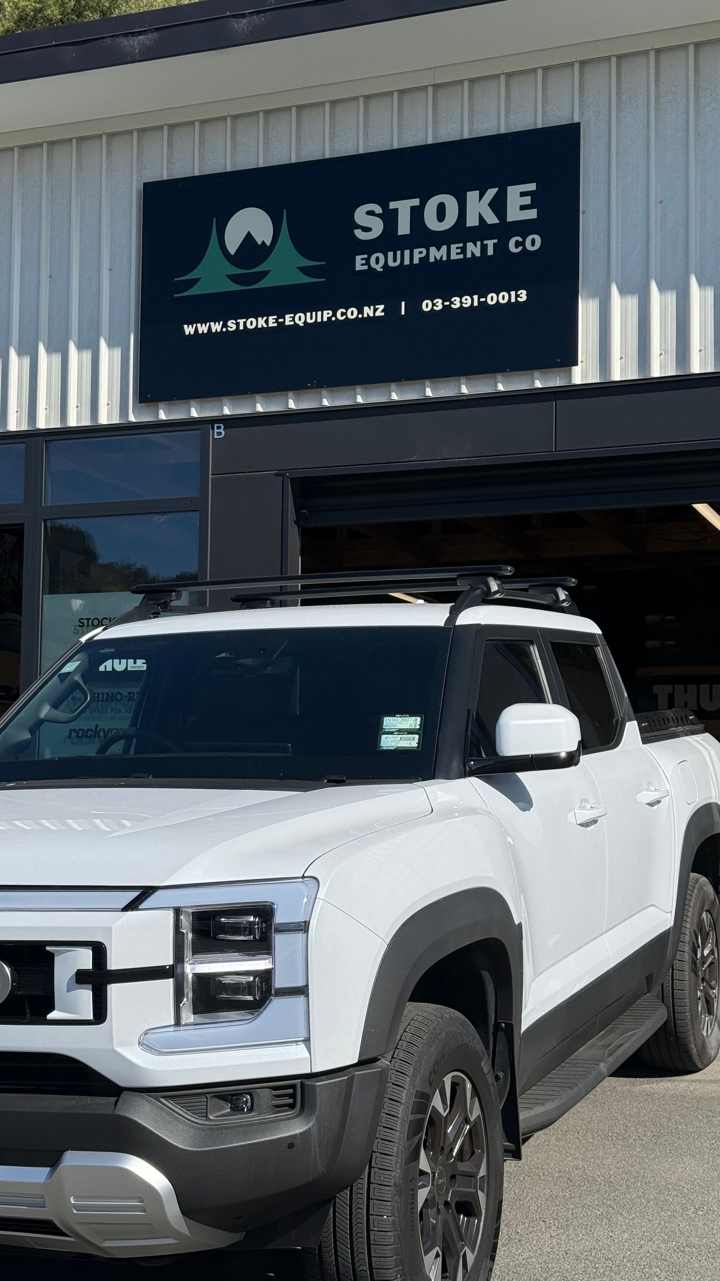 White BYD Shark 6 parked in front of Stoke Equipment Co building after being fitted with Thule WingBar Evo Roof Racks