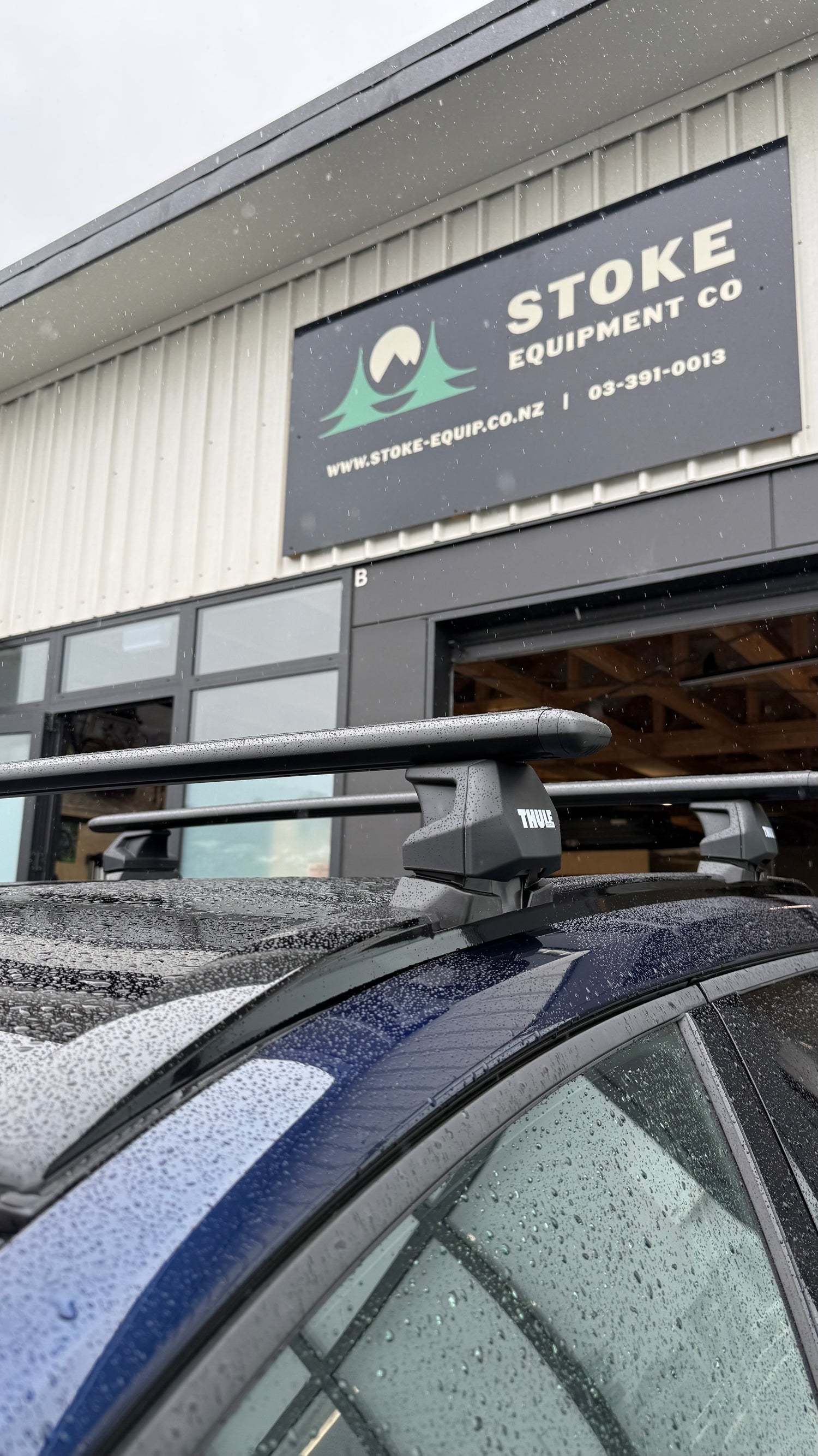 Car with wingbar evo roof rack in front of Stoke Equipment Co building
