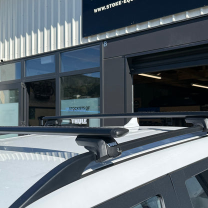 Car with roof rack in front of a building with a sign for Stoke Equipment Co.