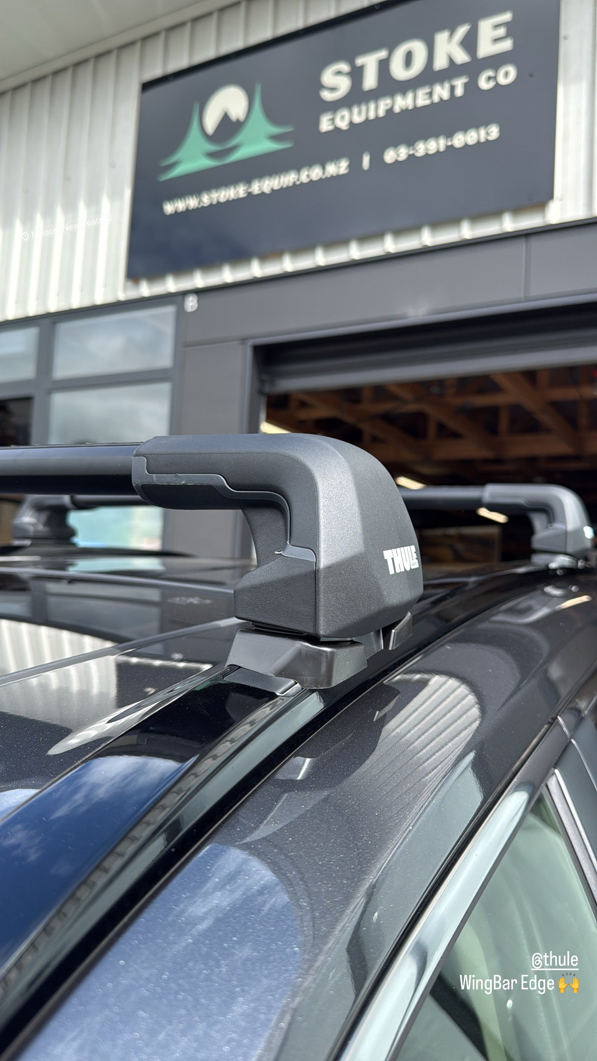 Thule WingBar Edge roof rack with sleek flush bar design on vehicle roof with 'Stoke Equipment Co' sign in the background
