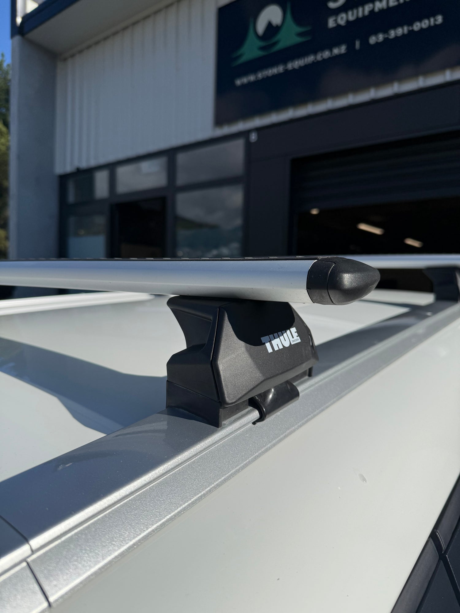 Close-up of a thule roof rack with a visible brand logo, parked in front of a building.