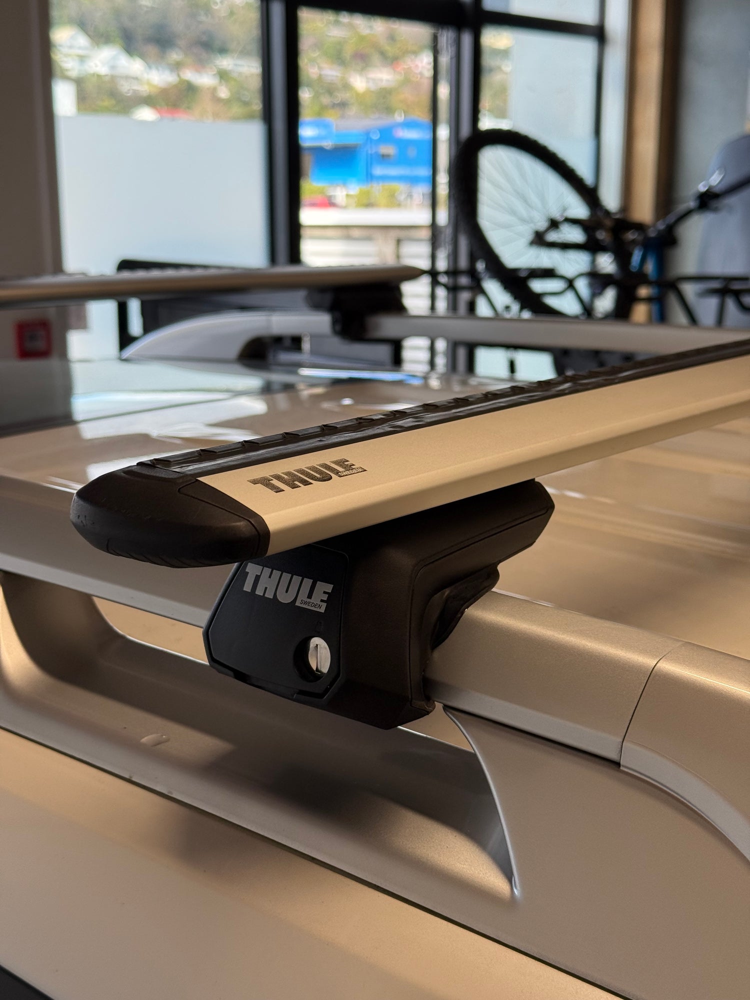 Close-up of a Thule wingbar evo silver roof rack attached to a vehicle with raised rails at stoke equipment co roof rack store in nelson new zealand