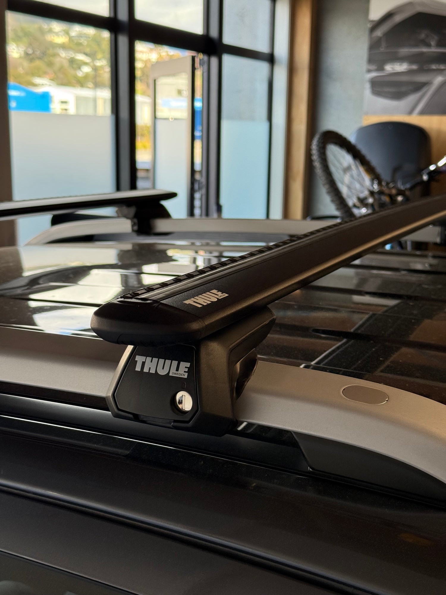 Close-up of a Thule wingbar evo black roof rack attached to a vehicle with raised rails at stoke equipment co roof rack store in nelson new zealand