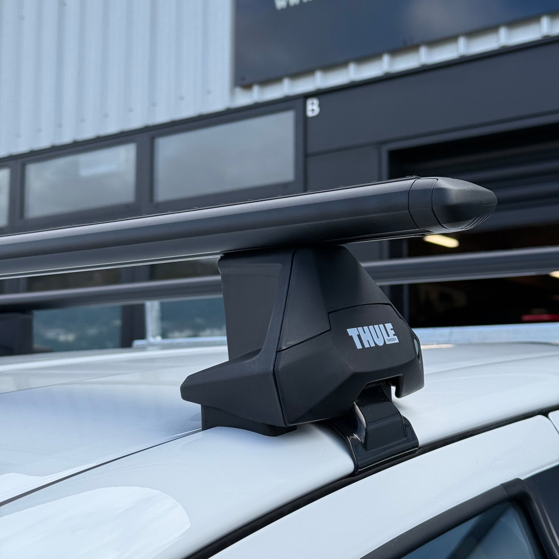 Close-up of a Thule wingbar evo black clamp mount roof rack attached to a vehicle with normal roof at stoke equipment co roof rack store in nelson new zealand