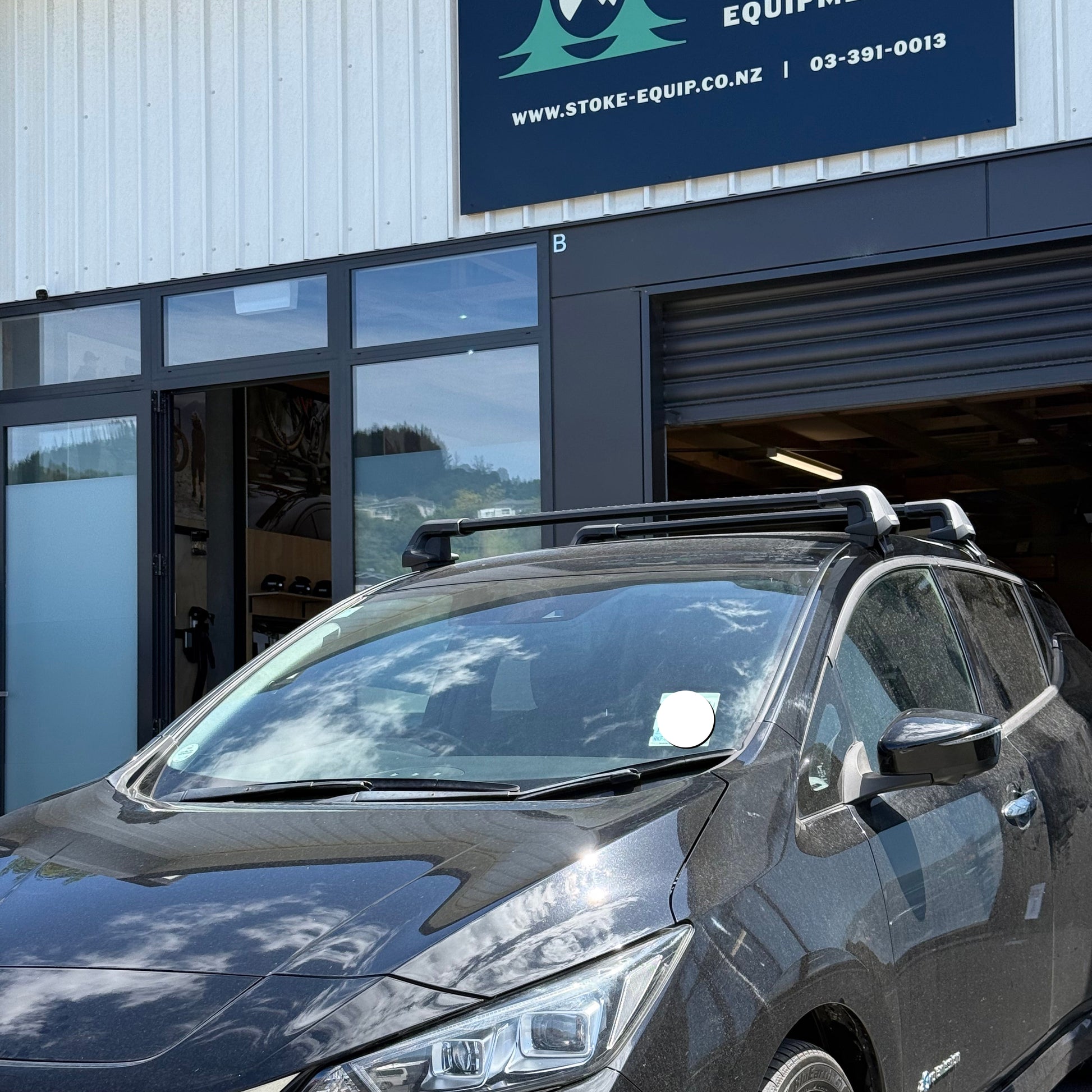 2018 nissan leaf with a thule wingbar edge black roof rack, parked outside stoke equipment co nelson