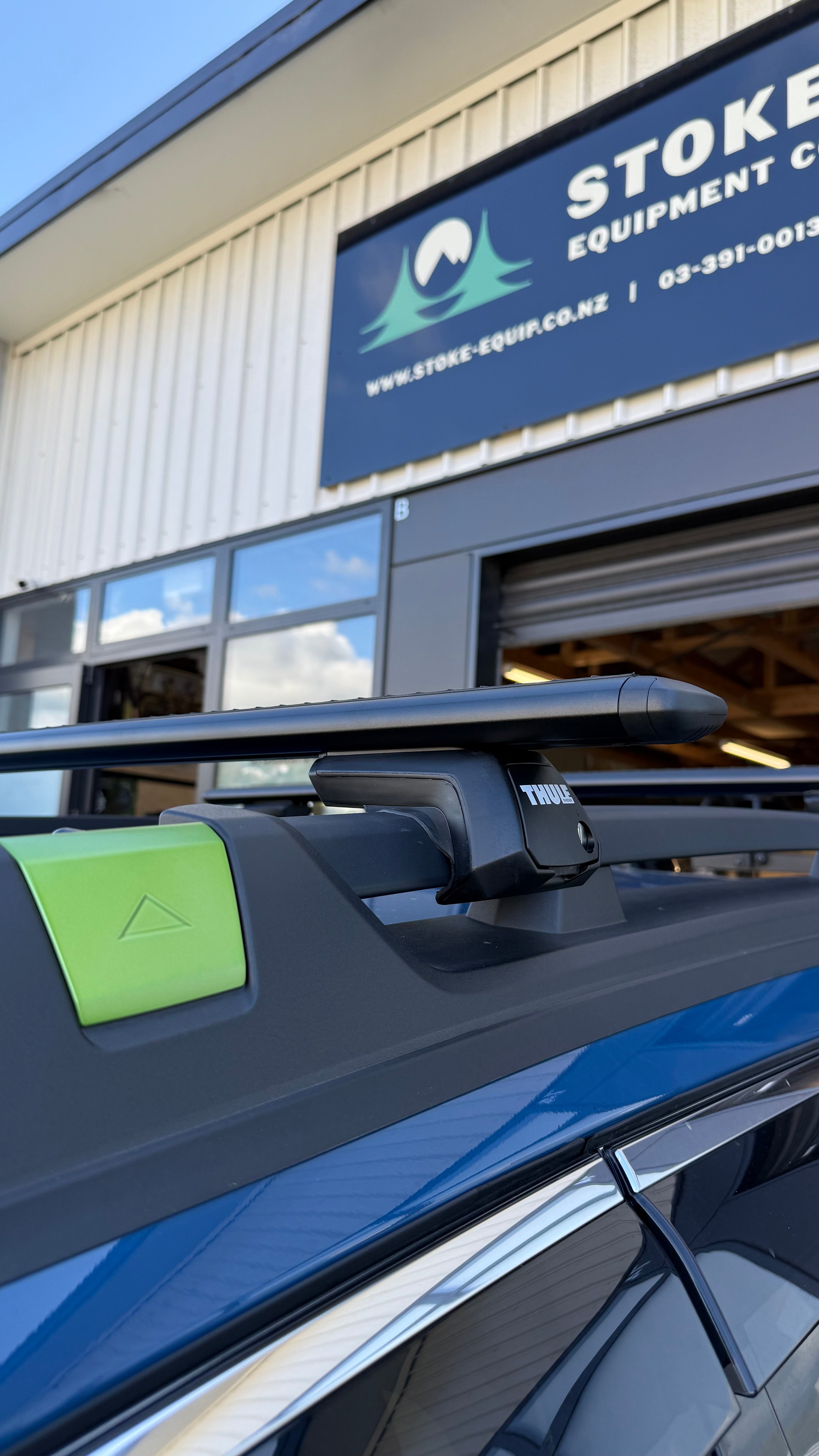 thule wingbar evo raise rail roof rack on a subaru outback, parked outside stoke equipment co roof rack store in nelson