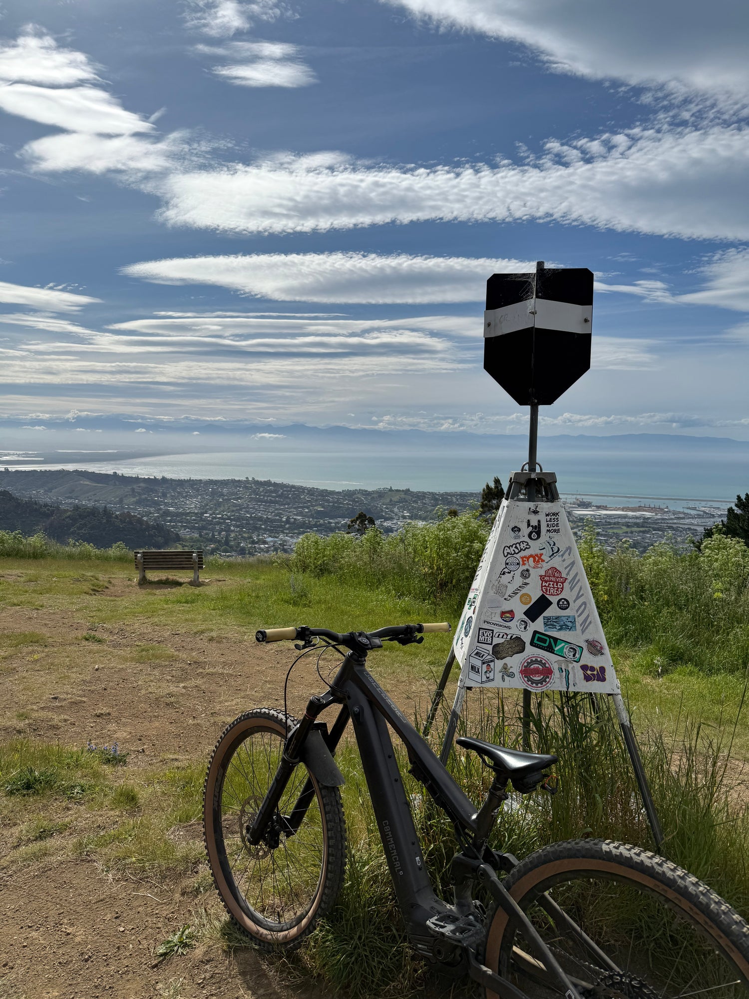 Bicycle leaning against the firball trig at Codgers MTB Trails with stickers, surrounded by a grassy area with a blue sky.