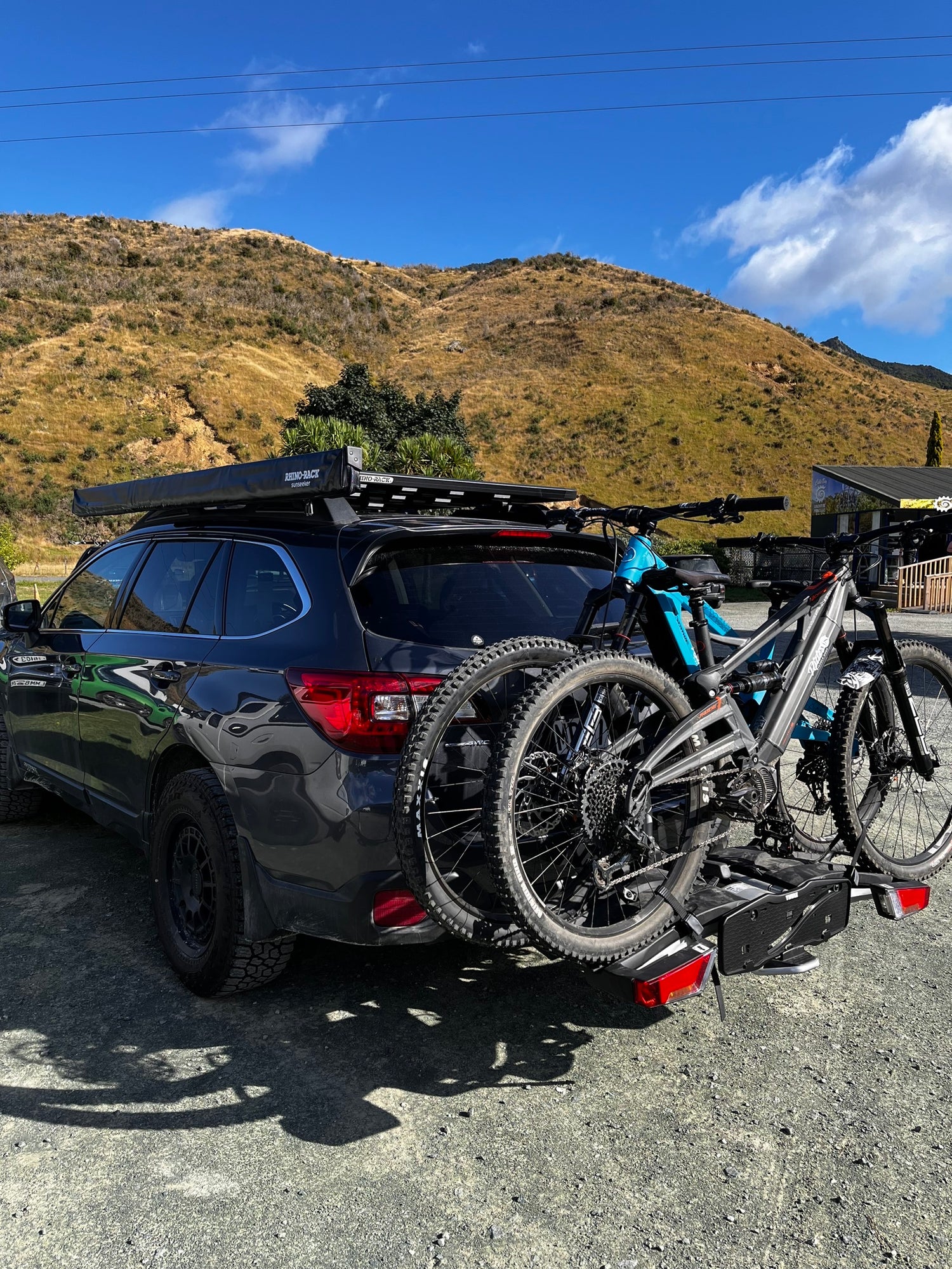 Subaru outback parked at cable bay adventure park, with 2 orange phase ebikes from Rider18 Nelson, sitting on a Thule EasyFold 932 Bike Rack.