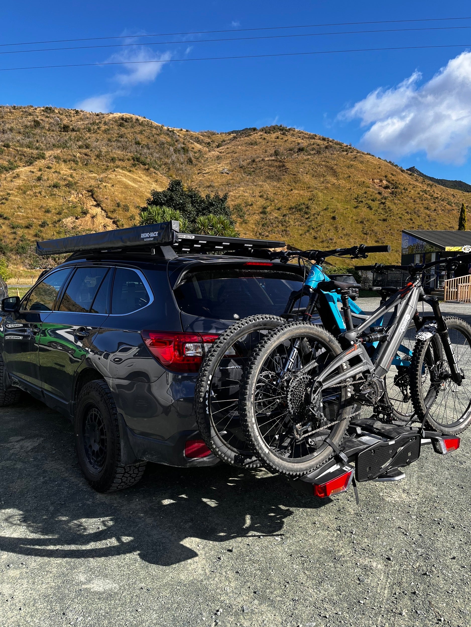 Subaru outback parked at cable bay adventure park, with 2 orange phase ebikes from Rider18 Nelson, sitting on a Thule EasyFold 932 Bike Rack.