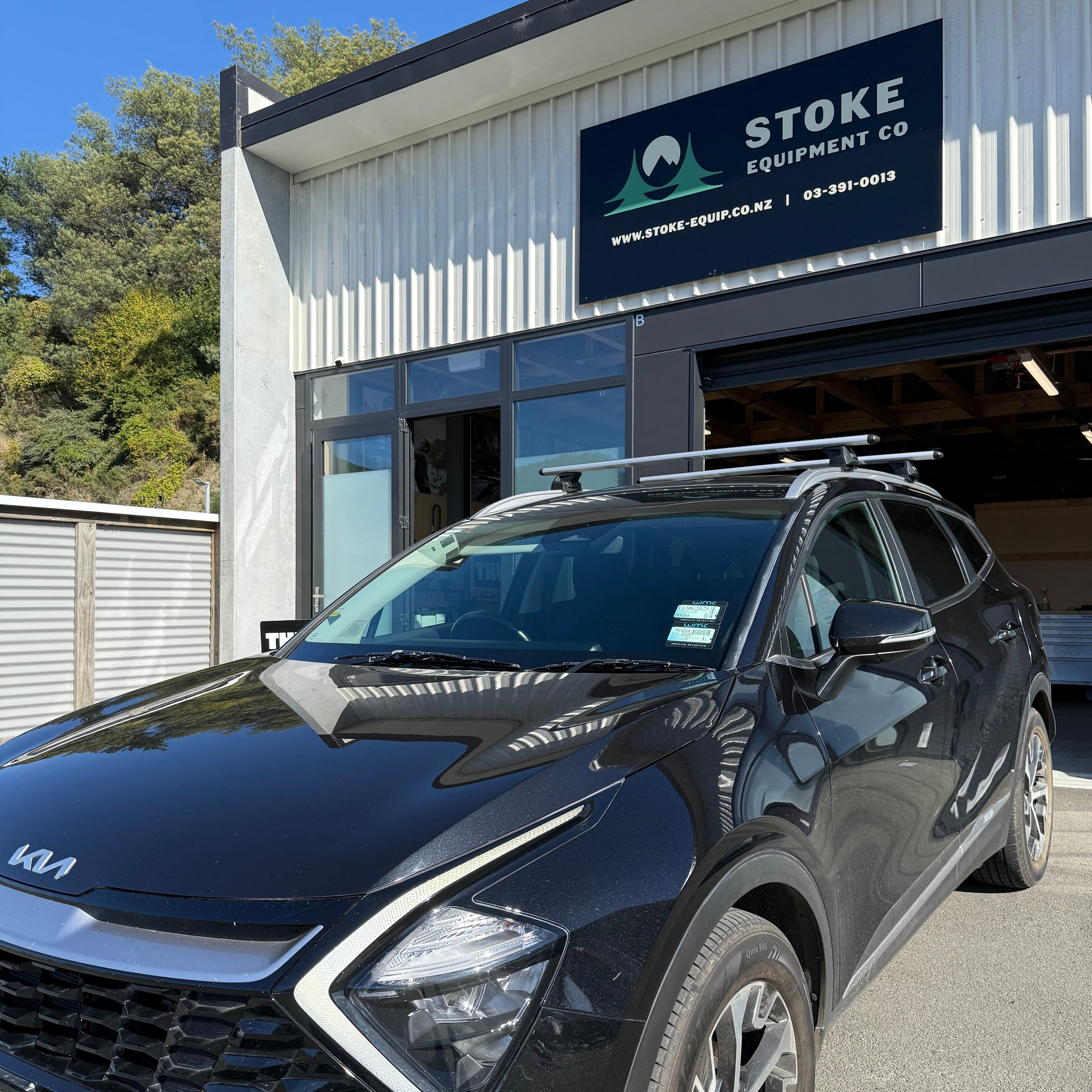 Kia sportage fitted with a thule wingbar evo flush rail roof rack system in silver, parked outside stoke equipment co roof rack store nelson new zealand