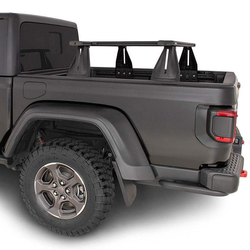 A matte dark gray Jeep Gladiator pickup truck with a black roof rack, shown from a rear three-quarter angle on a white background.