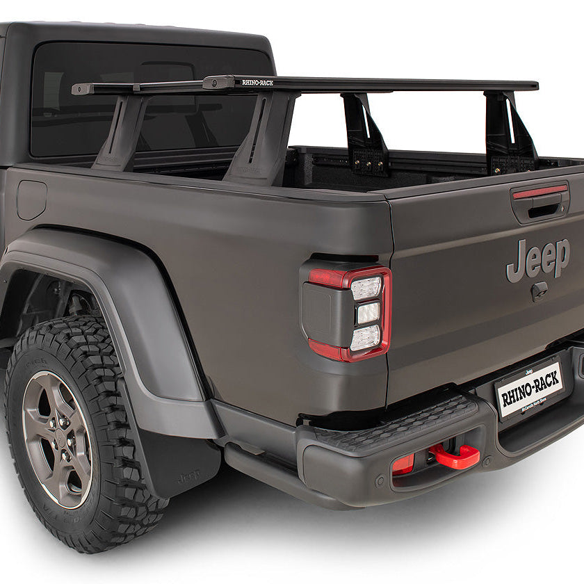 A dark gray Jeep Gladiator pickup truck shown from a rear three-quarter angle on a white background, featuring a black roof rack and a rear bumper cover with red accents. A 'BUNKER BAZAR' license plate is visible on the rear bumper.