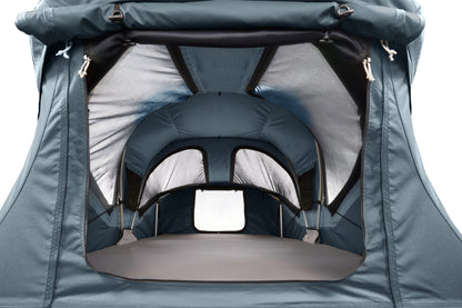 Close-up of the interior opening of a dark teal tent or canopy, showing gray and black inner lining, support straps, and a window cutout against a white background.