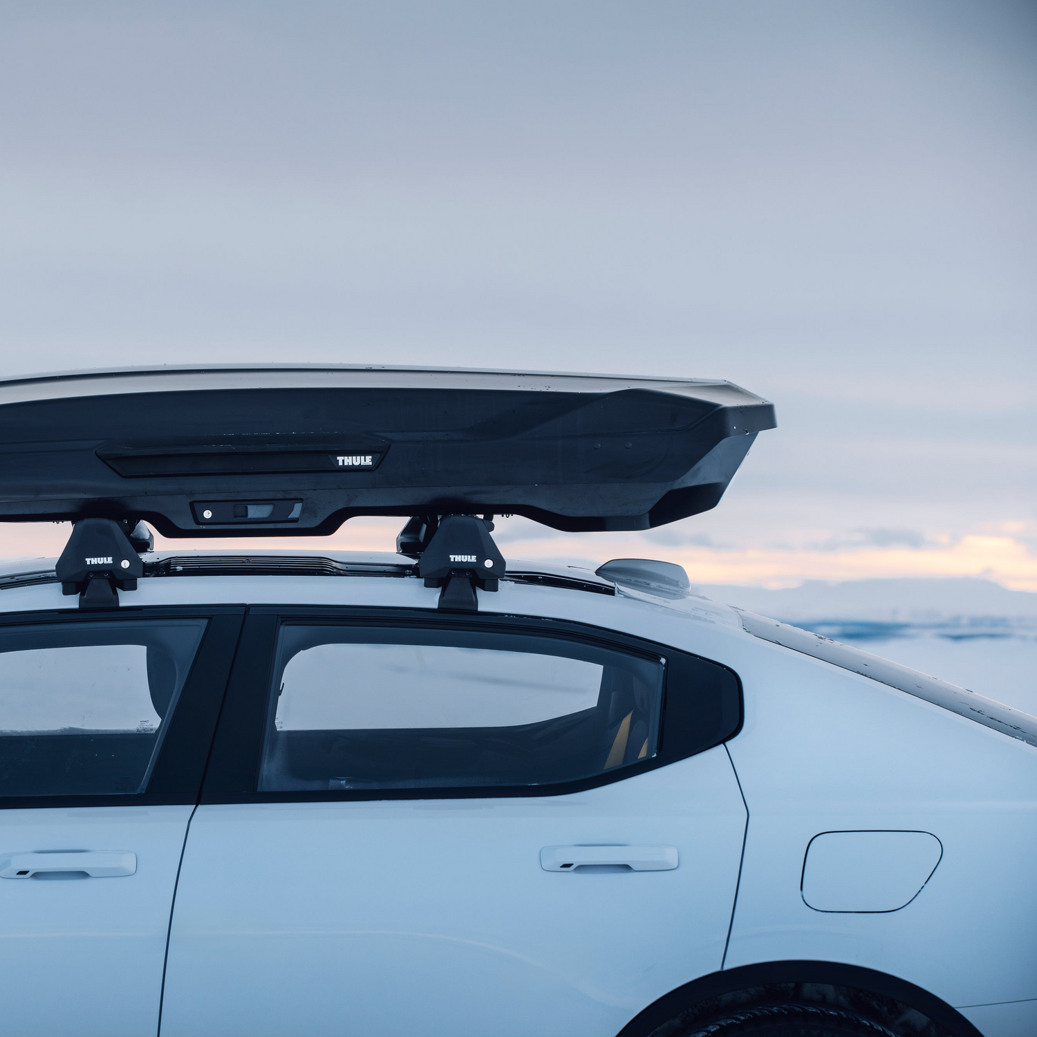 Car with a roof rack and roof box system against a cloudy sky