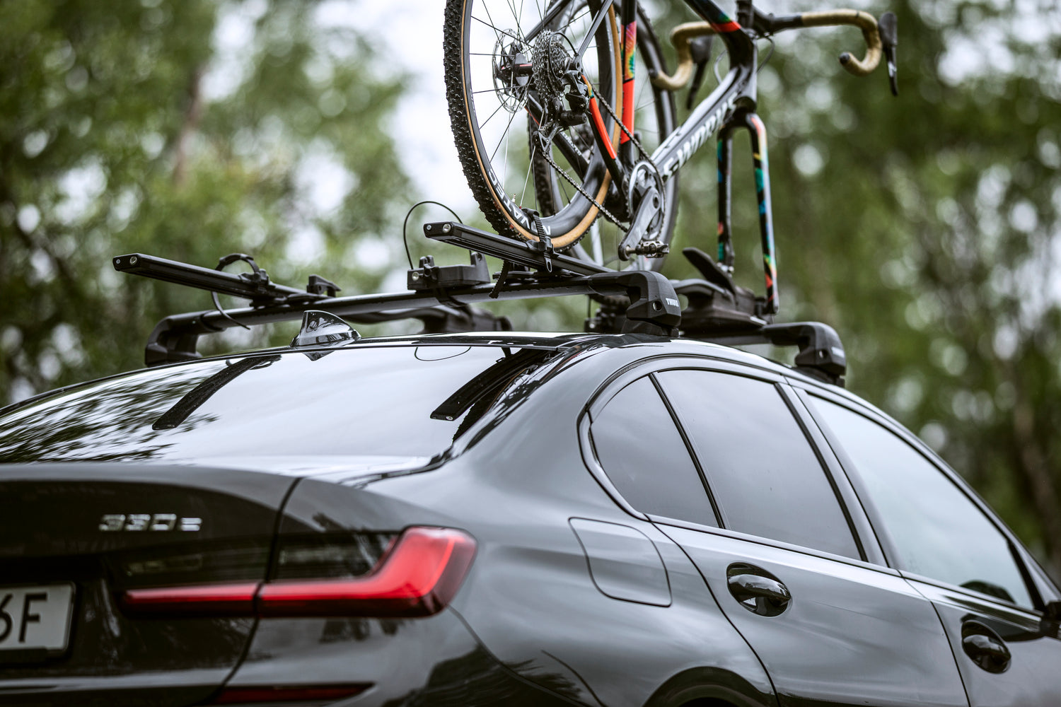 A set of black Thule Wingbar Edge Roof Racks on a black BMW, carrying a Specialized S-Works bike mounted to a Thule TopRide 568 Bike Carrier on top