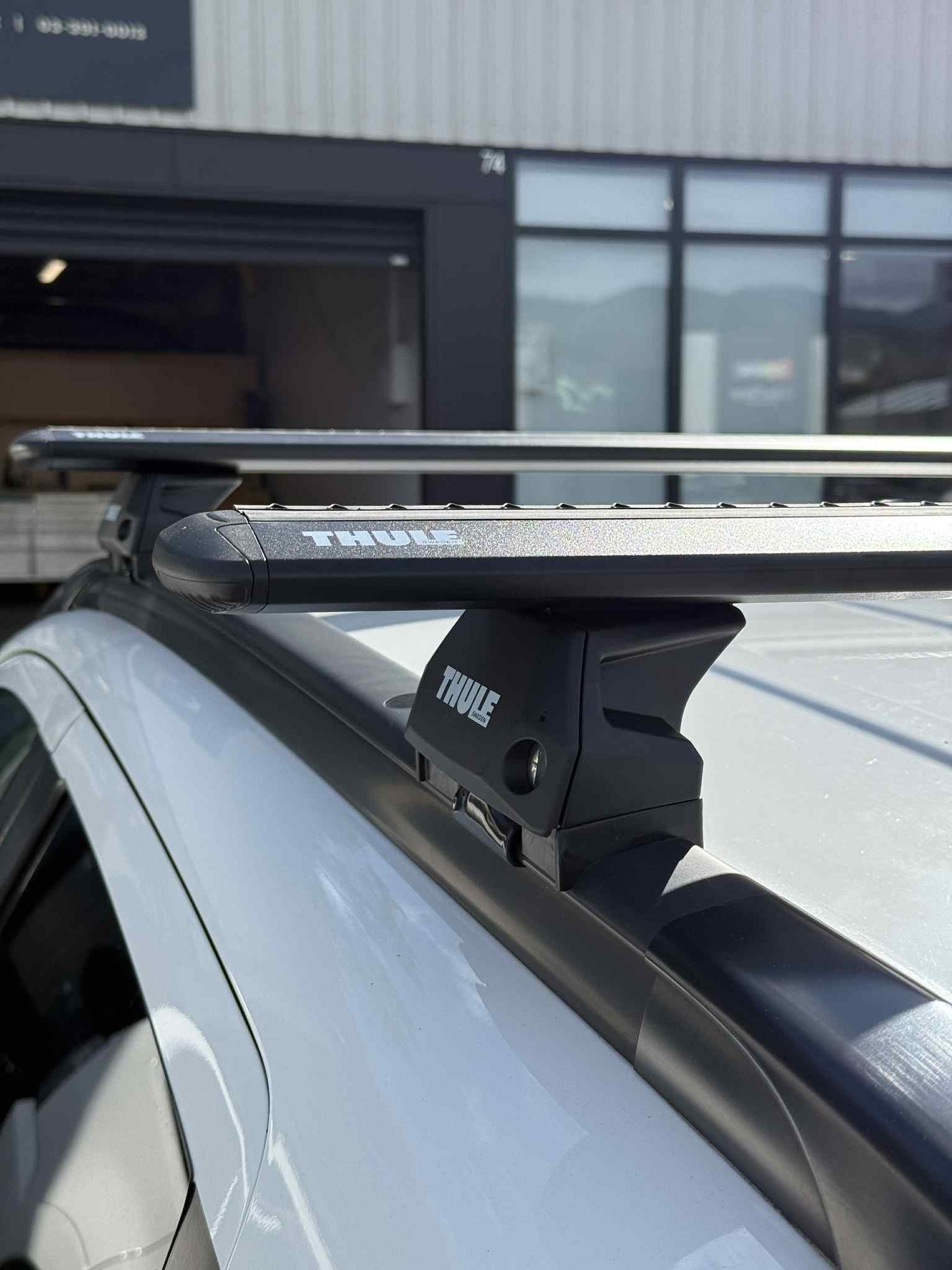 Thule black wingbar evo roof rack system on a car with a stoke equipment co roof rack store in the background