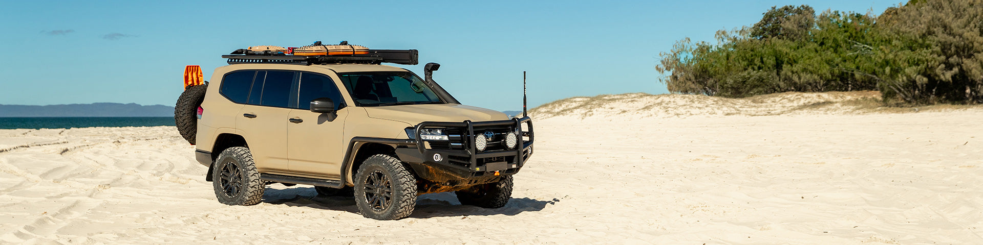 Rhino-Rack Roof Tray mounted on top of a Toyota Land Cruiser parked on a sandy beach