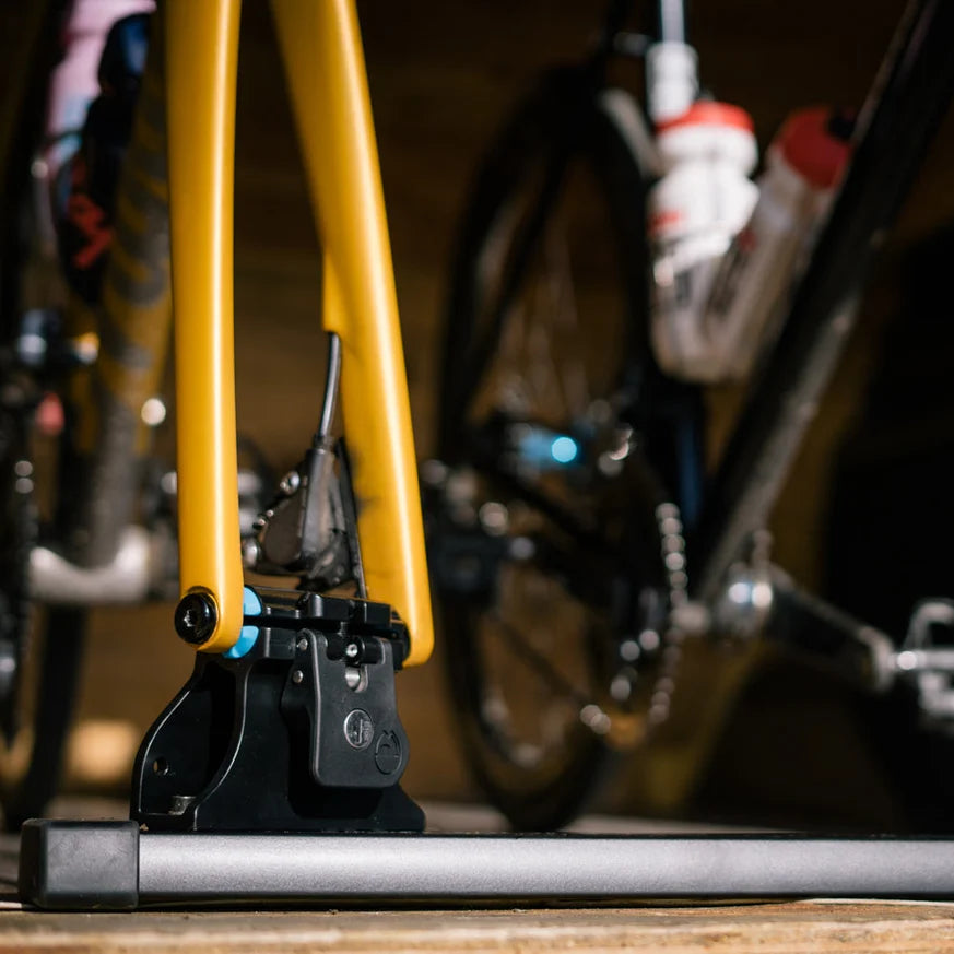 Close-up of a bicycle's yellow frame and black components on a wooden surface.