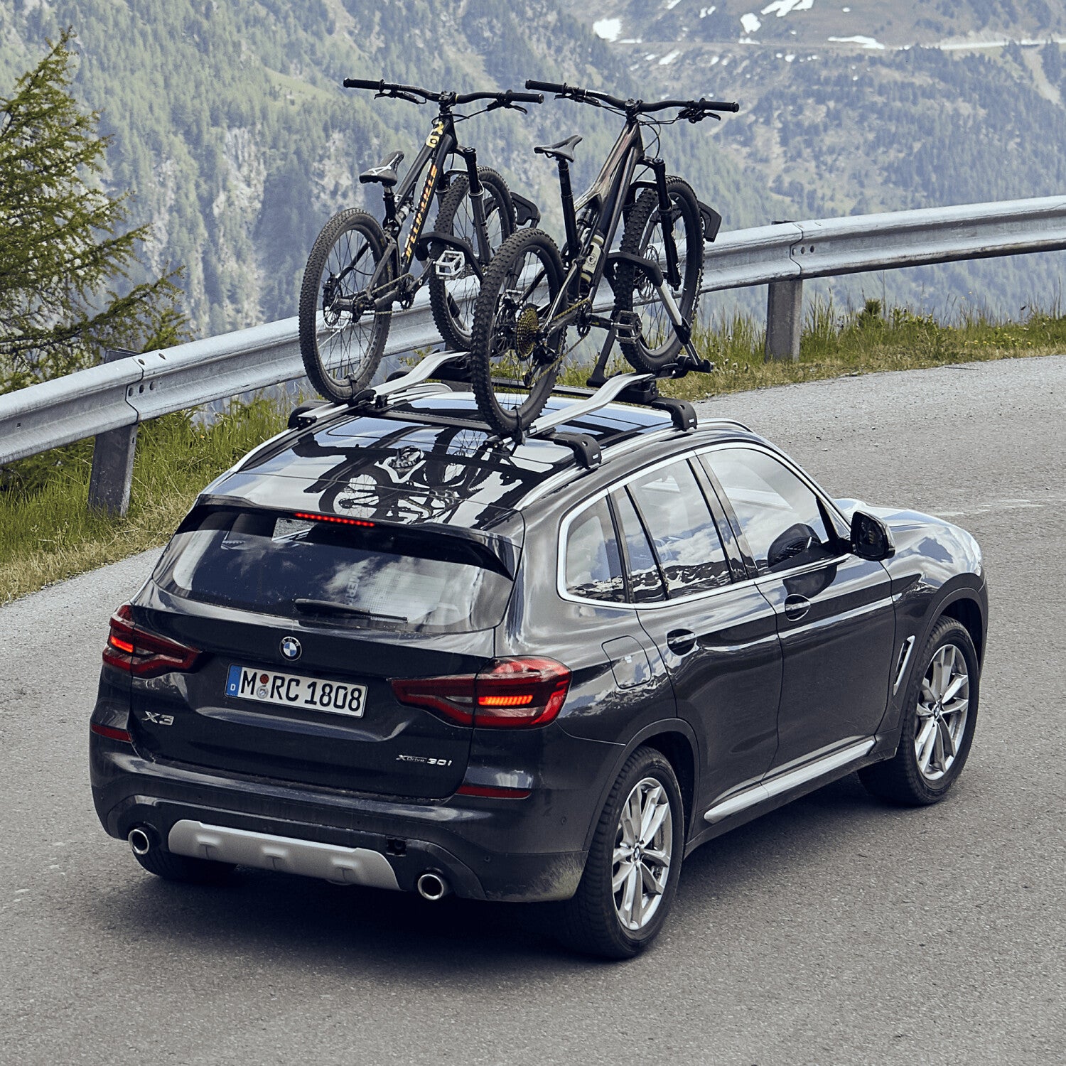 Black SUV with bicycles on a roof rack in a mountainous area
