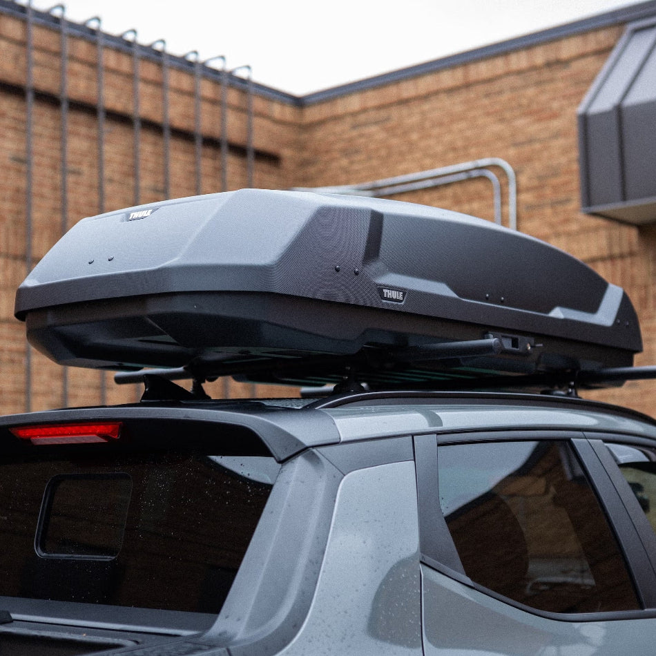 Car with a roof box attached, parked in front of a brick building.